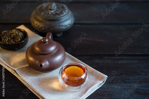 Teapot, incense and bowl with tea on light fabric and black wooden table