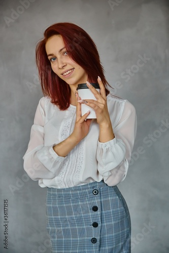 Beautiful redhead office woman in blue dress on grey background