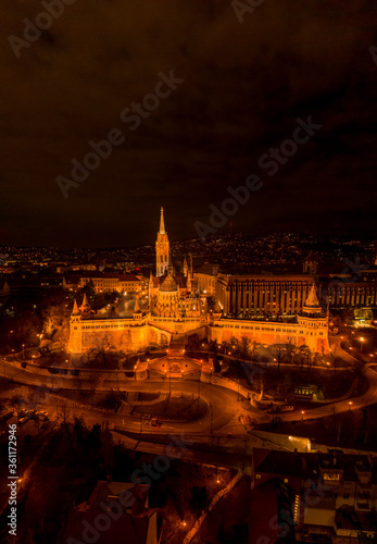 Aerial drone shot of Matthias Church with lights on Buda Hill in Budapest evening