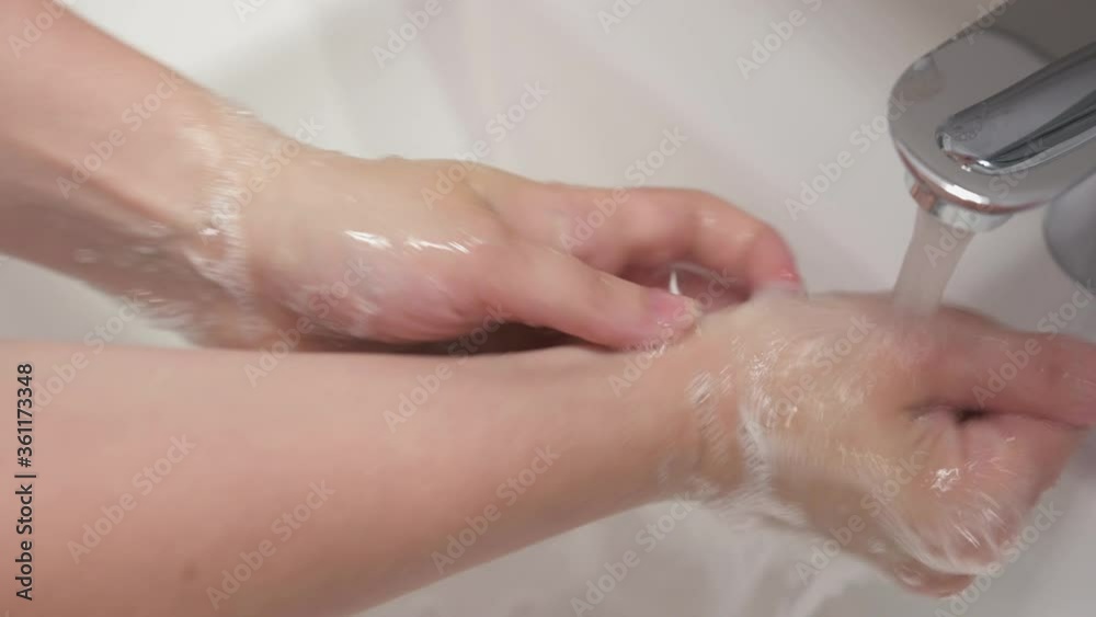 Female hand turning water tap. Close up girl washing hands with soap in bathroom at home to prevent coronavirus infection. Covid-19. Adult woman turning off tap. Female hand turning water tap. Close up girl washing hands with soap in bathroom at home to prevent coronavirus infection. Covid-19. Adult woman turning off tap.