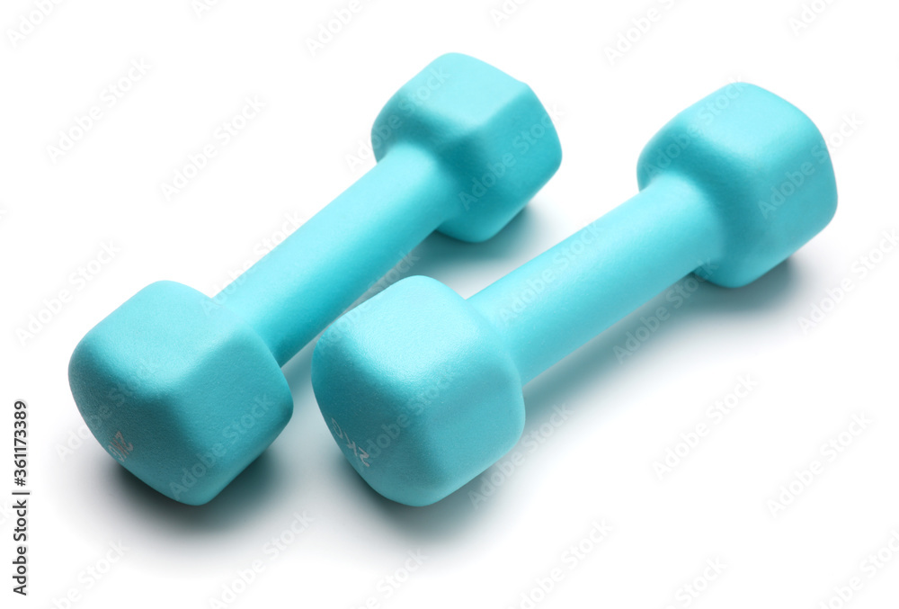 Two turquoise colored rubber dumbbells lying at white table Two turquoise colored rubber dumbbells lying at white table