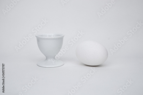 White egg on a white background, with a cup