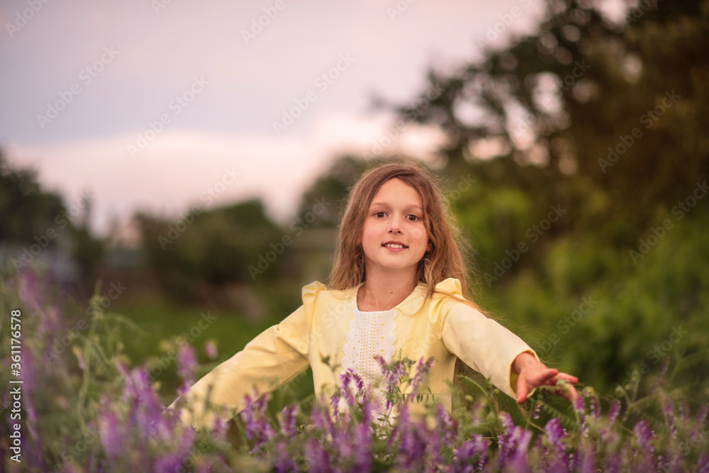 Beautiful girl at sunset in a field with purple flowers. Lavender. The child walks and travels. Rest and games. Long haired girl Beautiful girl at sunset in a field with purple flowers. Lavender. The child walks and travels. Rest and games. Long haired girl