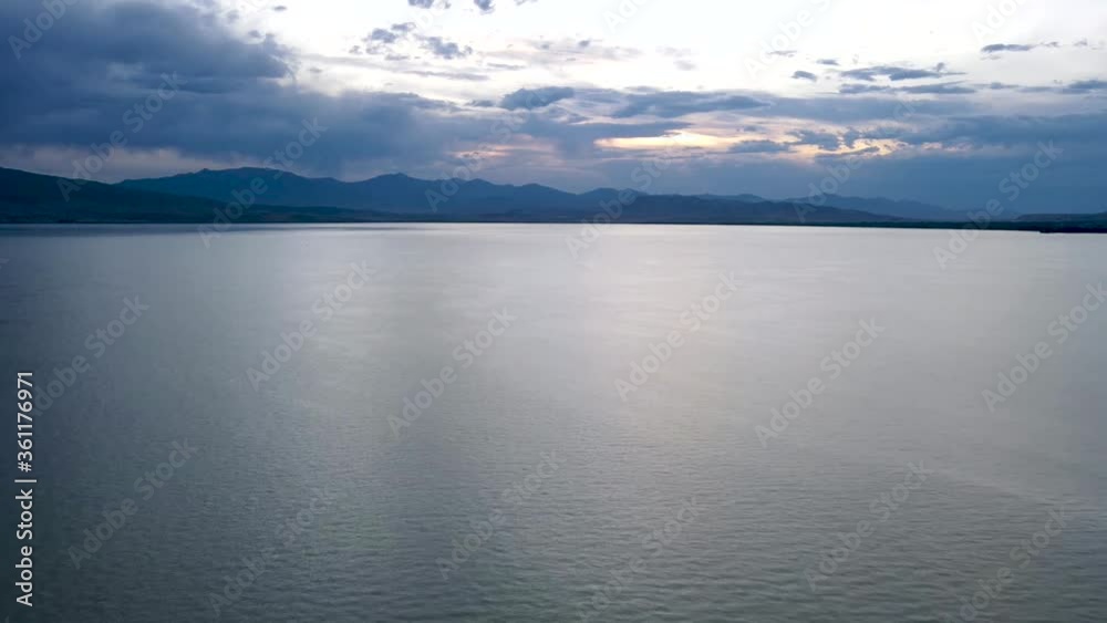 Hyperlapse: scenic view of Utah lake water with mountain range in background and low clouds in sky at sunset, pan Hyperlapse: scenic view of Utah lake water with mountain range in background and low clouds in sky at sunset, pan