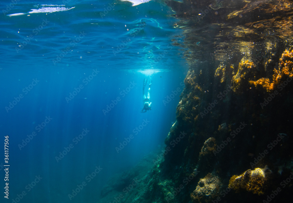 Obraz premium Beautiful girl swimming and freediving in the blue crystal clear mediterranean sea
