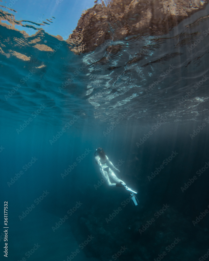 Fototapeta premium Beautiful girl swimming and freediving in the blue crystal clear mediterranean sea