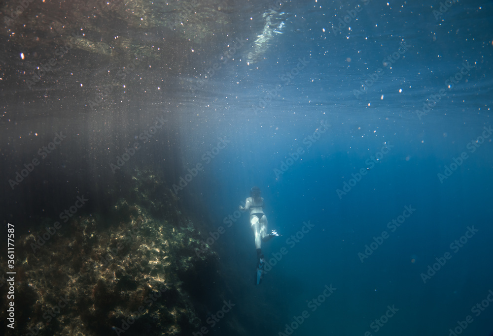 Obraz premium Beautiful girl swimming and freediving in the blue crystal clear mediterranean sea