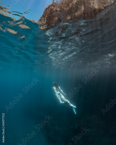 Beautiful girl swimming and freediving in the blue crystal clear mediterranean sea