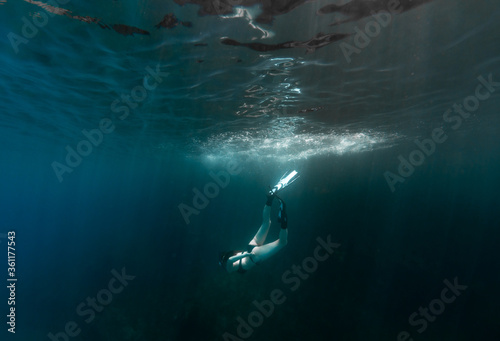 Beautiful girl swimming and freediving in the blue crystal clear mediterranean sea