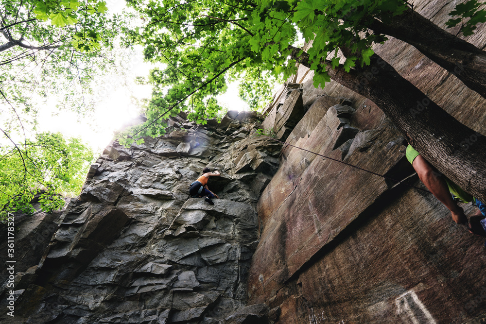 Fototapeta premium Climber extreme girl climbs a rock on a top rope. Summer of 2020, Buky canyon in Ukraine
