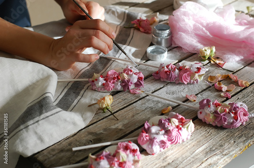 Hands paint a brush marshmallow in the form of a pony on sticks. Work at home. Horizontal photo.