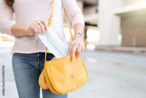 Woman Removing Face Mask From Purse
