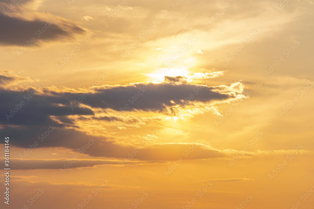 Fototapeta premium The sun shines through the evening dark clouds, the sunset.