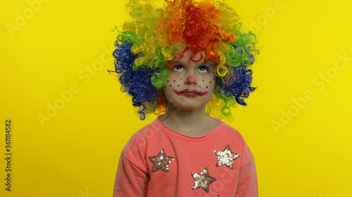 Little child girl clown in colorful wig making silly faces, having fun, smiling, dancing. Halloween