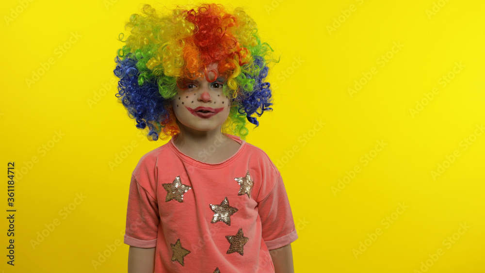 Little child girl clown in colorful wig making silly faces, having fun, smiling, dancing. Halloween Little child girl clown in colorful wig making silly faces, having fun, smiling, dancing. Halloween