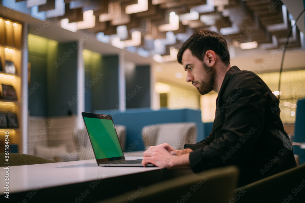 A man works on a laptop in an office or coworking A man works on a laptop in an office or coworking