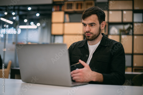 A man works on a laptop in an office or coworking