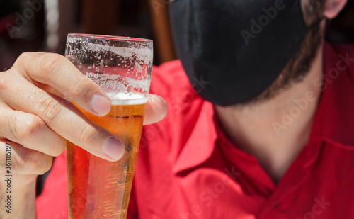 Men with protective face mask holding a glass of beer