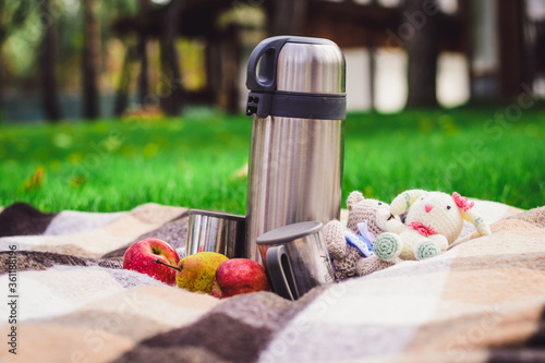 metal thermos with tea in nature. Hot tea in a cup on a camping trip.