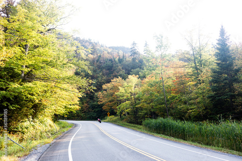 A distant motorcyclist leans into a curve through a autumnal landscape in Vermont.