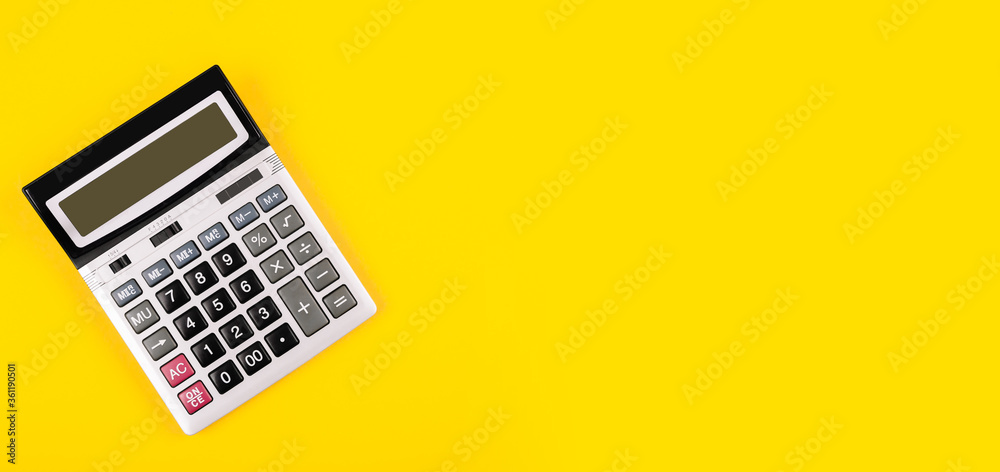 Large silver calculator with gray and black buttons on a yellow background. Conceptual photo of calculations, accounting, computing, profit, loss, tax. Large silver calculator with gray and black buttons on a yellow background. Conceptual photo of calculations, accounting, computing, profit, loss, tax.
