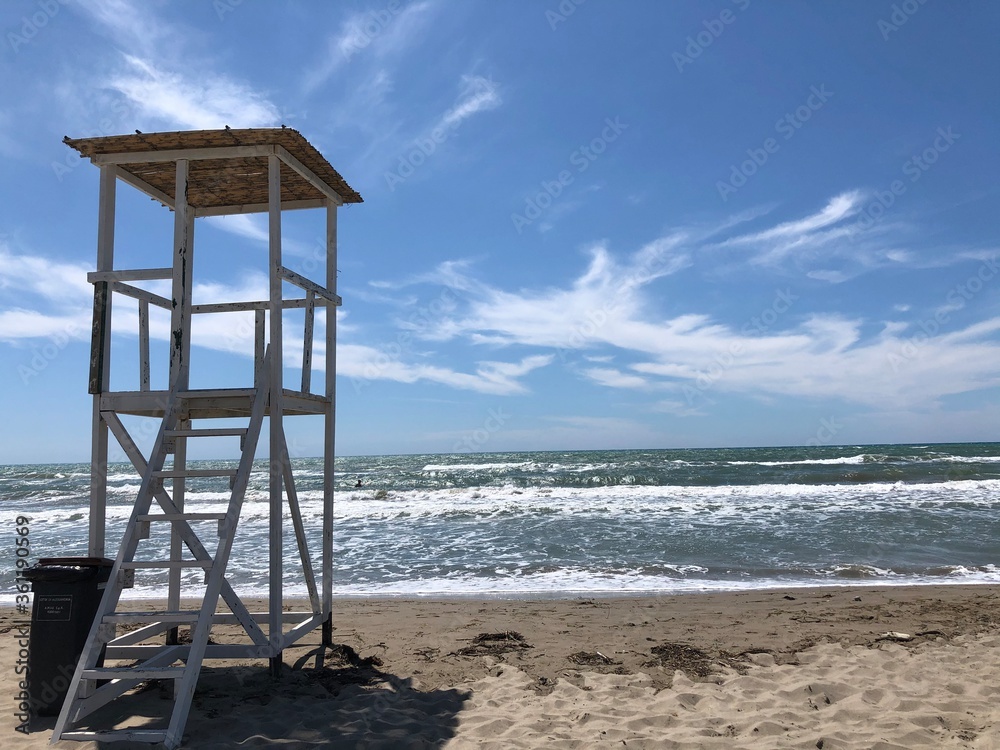 A white lifeguard tower on the beach . A white lifeguard tower on the beach .