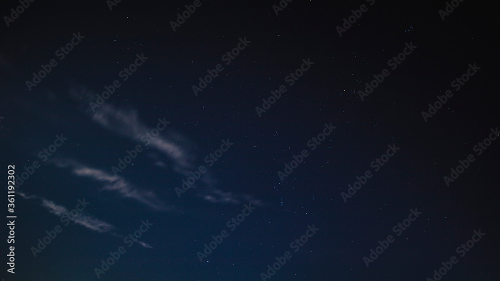 Spectacular landscape of a starry night with subtle blue tones and travelling lines of clouds in formation