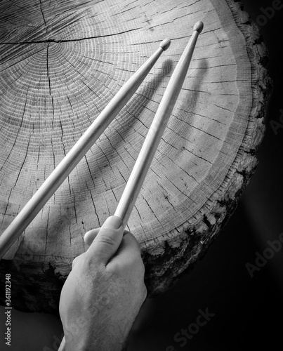 hands drumming with drumsticks on a log