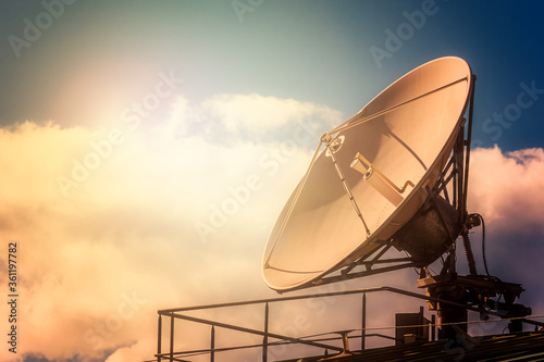 Parabolic tv antenna dish against sky with sunlight with copy sp