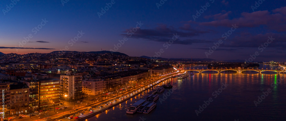 Panoramic aerial drone shot of quai by Danube river and Margaret Bridge after Budapest sunset