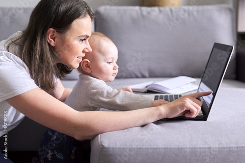 Young woman with toddler making video call, video conference using laptop at home photo