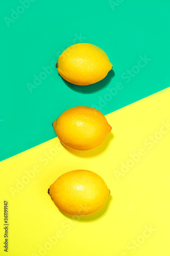 Creative layout made of lemons on bright yellow and trendy green blue background.