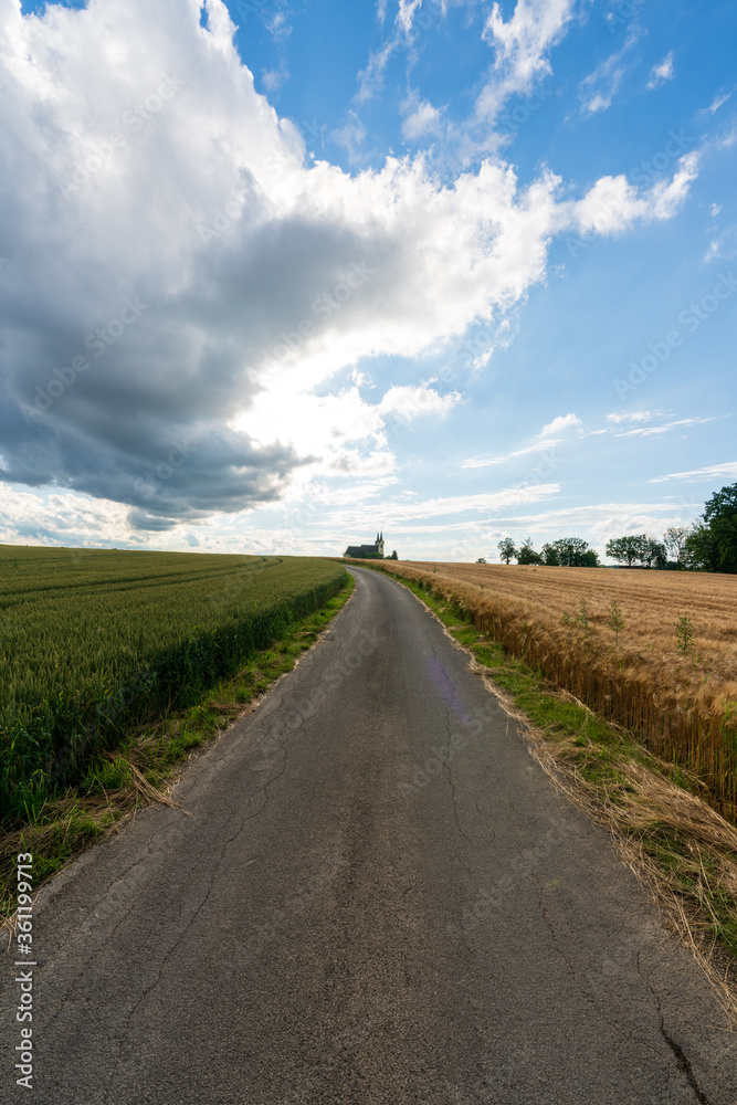 Weg zur Walfahrtskirche Heiligenkreuz bei Kremsmünster in Oberösterreich mit Regenwolken und Getreidefelder