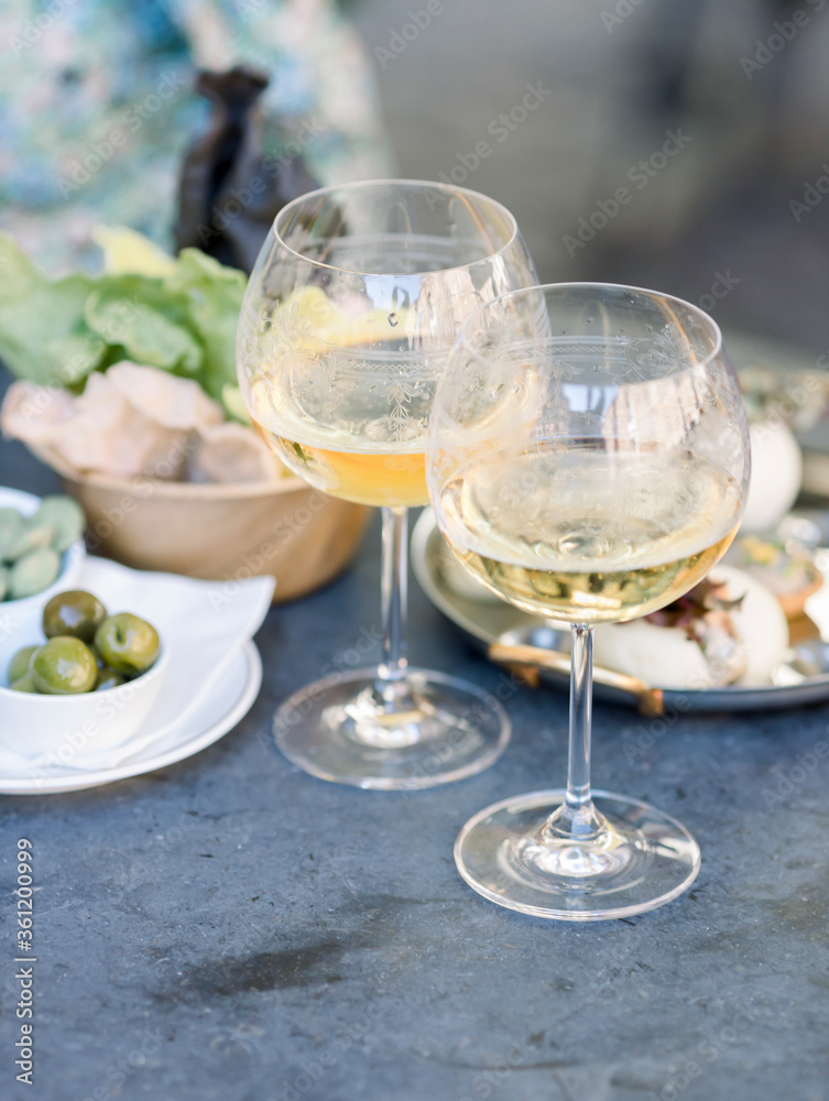 Obraz premium beautiful happy fashion woman drinking white wine with an aperitif. inner or aperitivo party concept. two glasses of wine