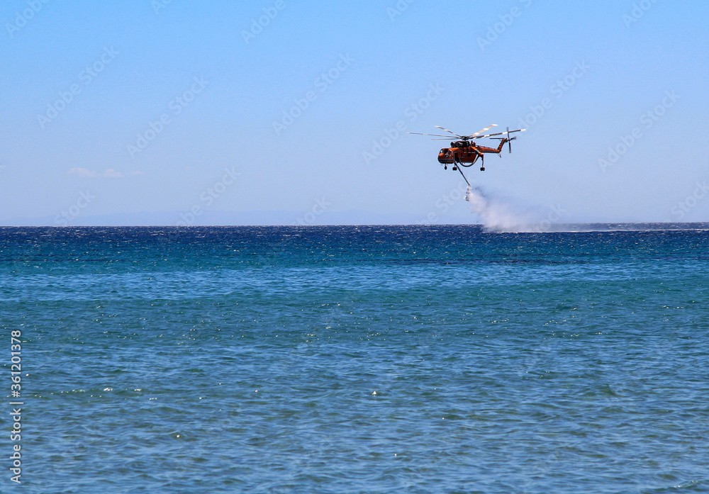 Helikopter straży pożarnej pobiera wodę z morza  - obrazy, fototapety, plakaty 