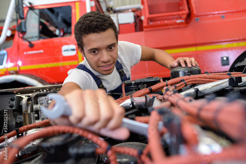 Wallpaper Mural smiling automechanic repairs the engine of a lorry or bus Torontodigital.ca