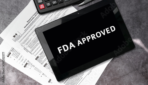 FDA approved on a black tablet and with tax forms and calculator