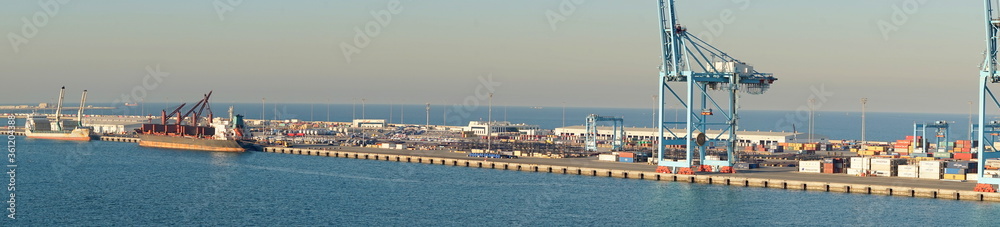 Industriehafen von Manama mit Verladekran und Schiff vor strahlend blauem Himmel