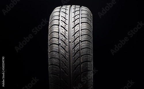 Car tire in dark color. Night shooting. The tread is summer. Light falls from above.