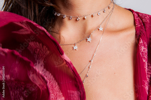 young woman chest closeup with necklaces and rings