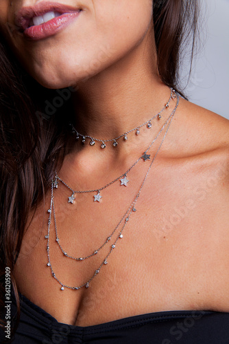 young woman chest closeup with necklaces and rings