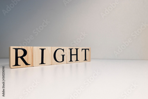 The word right from wooden cubes. Spot light and white background. Close up.