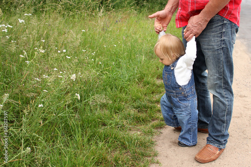 man teaches a little girl to walk, the concept of family relationships, first steps, children's curiosity, knowledge of the world, skills development photo