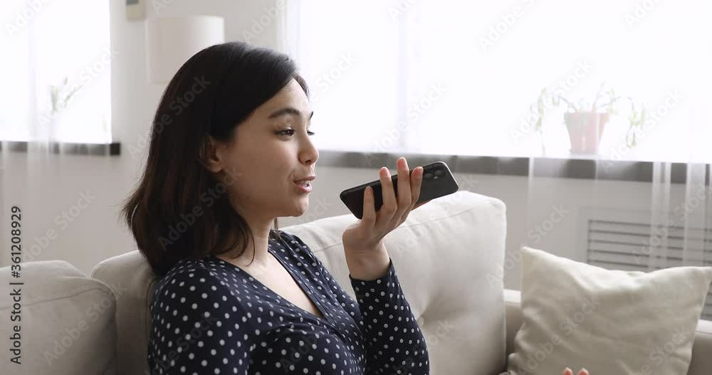 Pretty asian ethnicity young woman rest on couch holding smartphone uses loudspeaker speaks with boyfriend. Makes call contacts with mate distantly, modern tech, easy, apps speakerphone usage concept Pretty asian ethnicity young woman rest on couch holding smartphone uses loudspeaker speaks with boyfriend. Makes call contacts with mate distantly, modern tech, easy, apps speakerphone usage concept