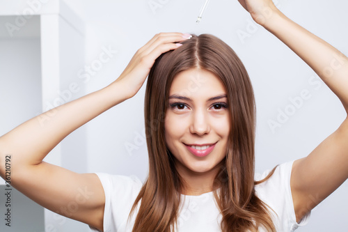 Young woman with luxurious hair applies conditioner for hair care