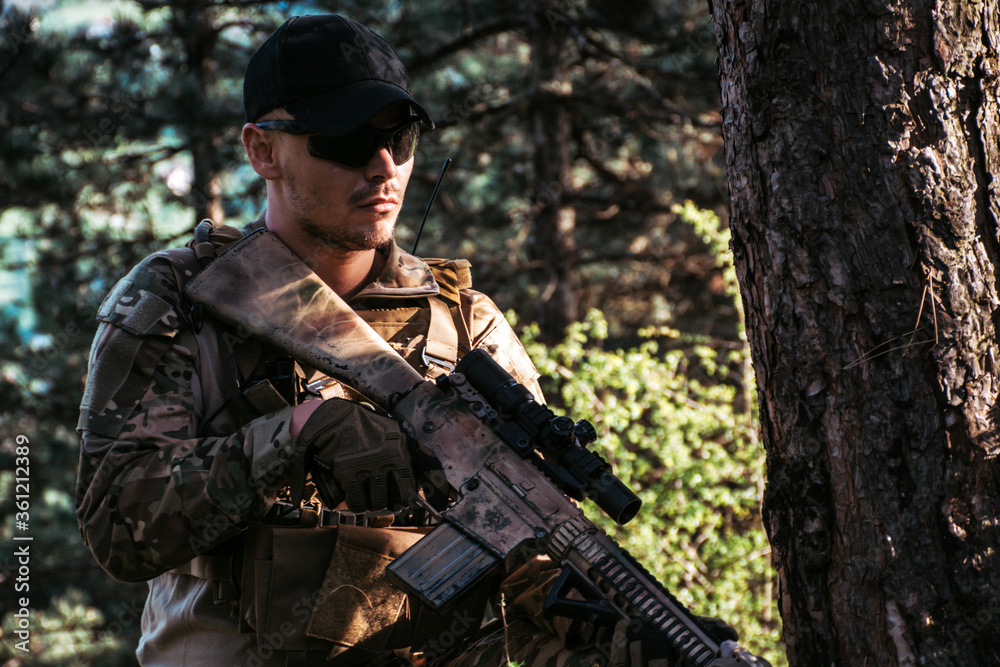 Fototapeta premium Soldier in a forest hiding in a foliage. Full equipment. soldier concept