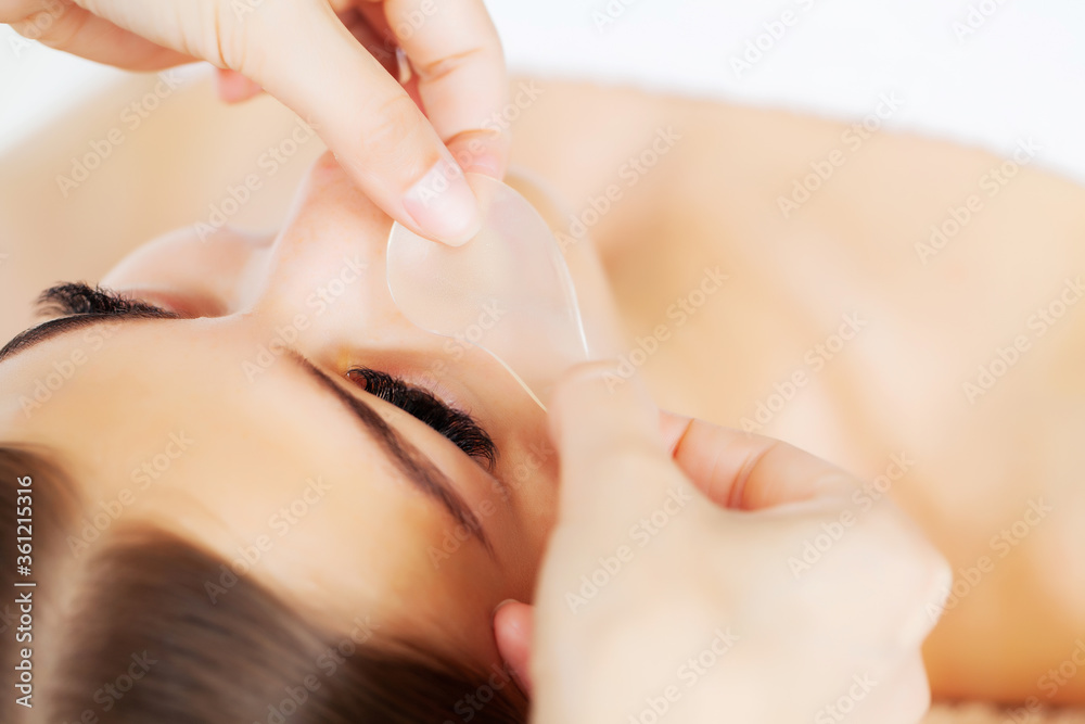 Naklejka premium Skin care under the eyes, patches are applied to the young woman's eyes
