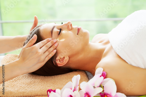 Young woman with beautiful face on facial massage in beauty studio