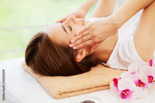 Young woman with beautiful face on facial massage in beauty studio