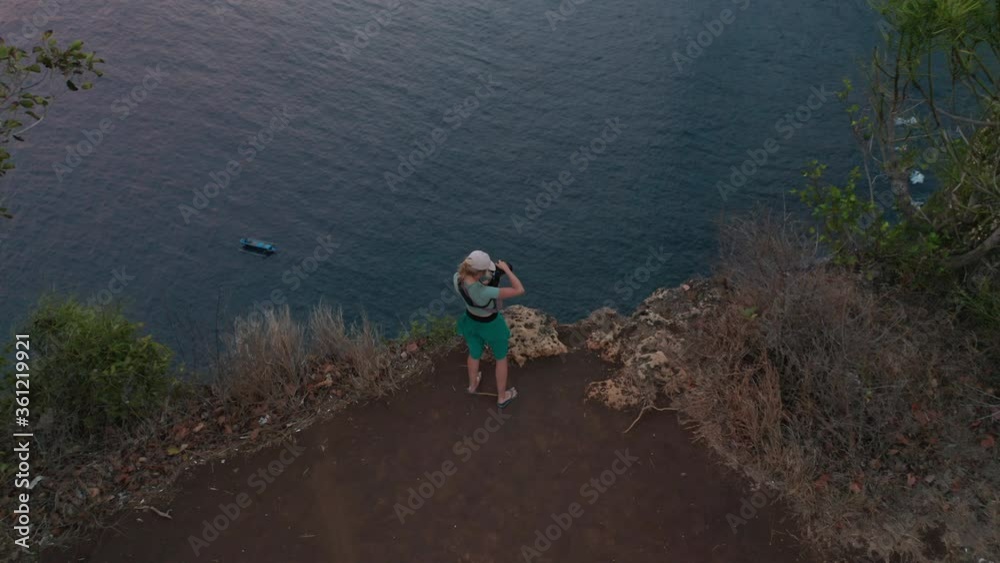Female Traveler with a Camera in Hand Taking Photos from Top of the Cliff Female Traveler with a Camera in Hand Taking Photos from Top of the Cliff
